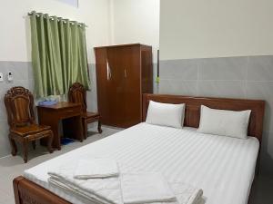 Lai VungKhách sạn Hoàng Gia - TT Lai Vung的一间卧室配有一张床、一张桌子和一把椅子