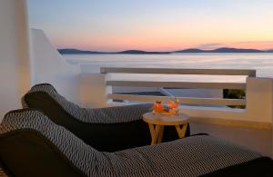 圣爱奥尼斯米科诺斯瓦纳卡Spa度假酒店的阳台配有两把椅子和一张桌子,享有日落美景。