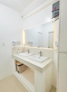马尼拉NomadsMNL Hostel的白色的浴室设有两个盥洗盆和镜子