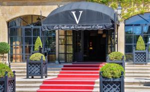 圣雷米普罗旺斯勒瓦隆德瓦鲁格温泉酒店的红色地毯楼梯通往带黑色雨伞的建筑