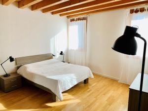 罗维戈Appartamento Donà的卧室配有白色的床和黑灯