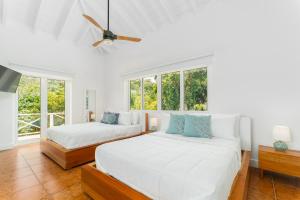 西湾Blue Roatan Resort的白色客房的两张床,设有窗户