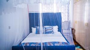 内罗毕Primal apartment at Embakasi, Nairobi, Kenya.的一张蓝色和白色的天蓬床