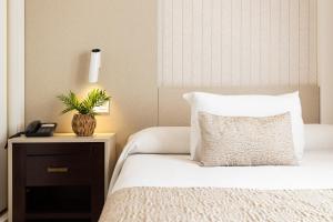 马拉加Hotel Plaza Del Castillo的一间卧室配有带枕头和床头柜的床