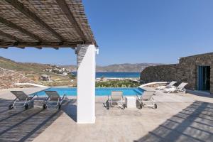 帕诺尔莫斯米科诺斯Elegant Mykonos Villa Air Private Pool 4 Bedrooms Sea View Panormos的一组椅子坐在泳池旁的庭院里