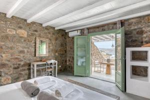 帕诺尔莫斯米科诺斯Elegant Mykonos Villa Air Private Pool 4 Bedrooms Sea View Panormos的石墙客房设有浴缸和门。