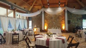 塔尔萨波斯托克度假山林小屋的宴会厅配有桌椅和白色窗帘