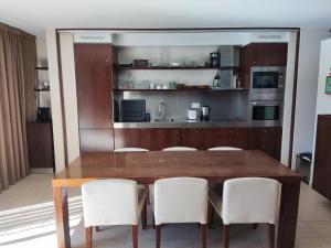 阿尔布费拉Salgados Beach&Golf - Praia dos Salgados的厨房配有木桌和白色椅子