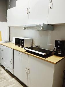 马德里Rio Hostel的厨房配有白色橱柜、水槽和微波炉