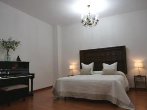 赫雷斯-德拉弗龙特拉Villa María Montecastillo Golf的一间卧室配有一张带钢琴和吊灯的床。
