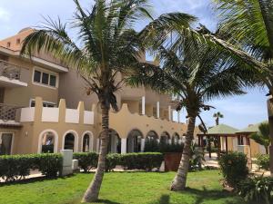 圣玛丽亚Tropical Morabeza Apartment Santa Maria的两棵棕榈树,在一座建筑前