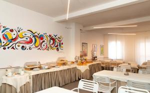 西维尔诺瓦·马尔凯日光浴酒店 的餐厅设有桌椅,墙上挂有绘画作品