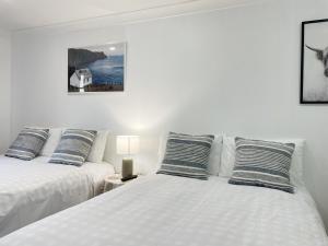 奥克兰Pupuke Manor Motel的配有2张床的带白色床单和枕头的客房