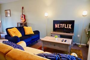 雷纳姆Secluded 4 Bed Detached House with Driveway的客厅配有蓝色的沙发和电视