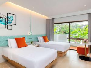 港生Novotel Rayong Rim Pae Resort的带窗户的客房内的两张床