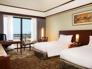 马尼拉Sofitel Philippine Plaza Manila的酒店客房配有两张床和一张书桌