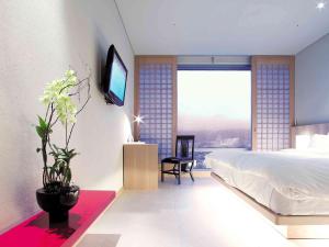 昌原市Grand Mercure Ambassador Changwon的一间卧室配有一张床,墙上配有电视