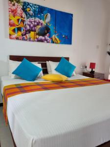 卡尔皮蒂耶Wellé Wadiya Beach Villa的一间卧室配有白色的床和蓝色和黄色枕头