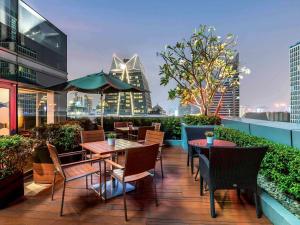 曼谷Novotel Bangkok Ploenchit Sukhumvit的大楼顶部带桌椅的天井