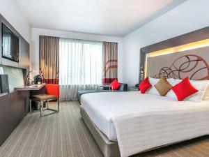 曼谷Novotel Bangkok Ploenchit Sukhumvit的酒店客房配有一张带红色枕头的大床