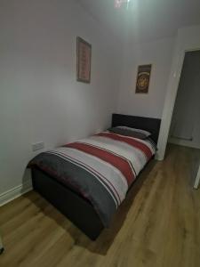 KentLangley Haven - 3 BR House的白色墙壁和木地板的客房内的一张床位