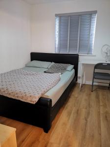 KentLangley Haven - 3 BR House的一间卧室配有一张床、一张桌子和一个窗户。