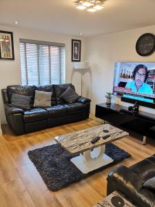 KentLangley Haven - 3 BR House的客厅配有黑色真皮沙发和电视