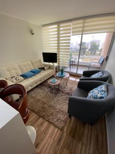 康康Departamento en Bosques de Montemar的客厅配有沙发、椅子和电视