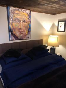 达沃斯Chalet OG Harfe的卧室配有一张蓝色的床,墙上挂着一幅画