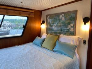 SavannaThe Lily Pad Boatel Houseboat的卧室配有带枕头的床铺和窗户。