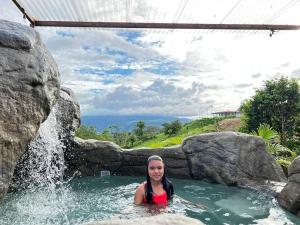 福尔图纳Villas Altos del Arenal的瀑布中热水浴池中的女人