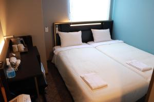 东京ICI HOTEL Tokyo Hatchobori的卧室配有一张带白色床单的大床和窗户。