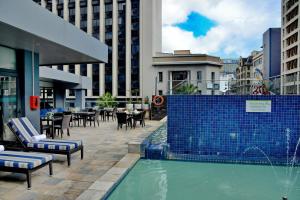 开普敦Cresta Grande Cape Town的城市中一个带桌椅的游泳池