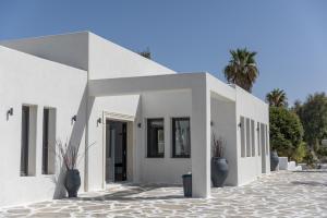 纳克索乔拉Naxos Village hotel的前面有盆栽植物的白色建筑