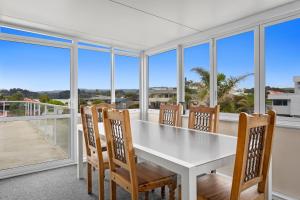 奥霍普海滩Treasure on Tawai - Ohope Holiday Home的一间配备有白色桌椅的用餐室