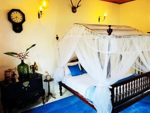 贝鲁沃勒Sriyan Villa的一间卧室配有一张天蓬床,墙上挂着一个时钟