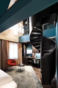 格拉茨Aiola Living Graz的酒店客房设有螺旋楼梯和红色椅子。