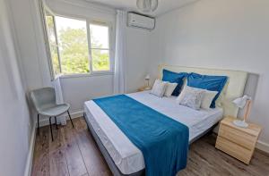 圣吉尔莱班L'Eden Blue à Saint Gilles les Bains, magnifique vue mer的一间卧室配有一张带蓝色床单的床和一扇窗户。