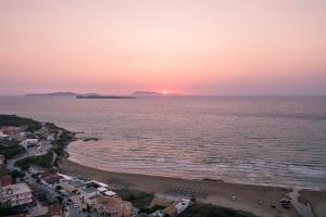 圣斯特凡诺斯Sunsea Wellness Resort的海滩上的日落,小镇和海洋