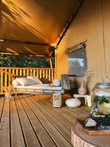ŁowyńFreedolina Glamping的木制甲板上的帐篷,配有一张床