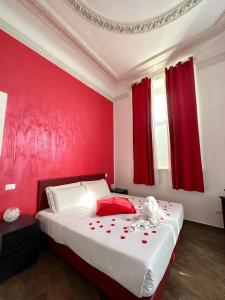 罗马首都神殿旅馆的一间红色墙壁的卧室和一张红色窗帘的床