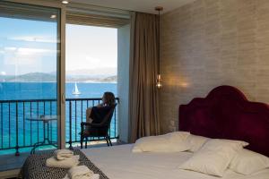 利勒鲁斯Hotel La Pietra Restaurant & Spa的坐在酒店带阳台的房间里椅子上的女人