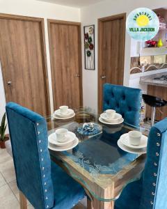 拉特瓦伊达Villa Jackson的一间设有玻璃桌和蓝色椅子的用餐室