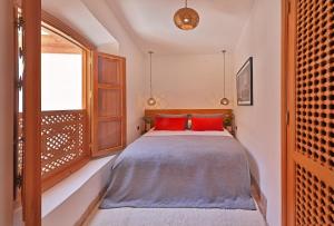 马拉喀什RIAD THE MILESTONE的一间卧室配有一张带红色枕头的床和一扇窗户