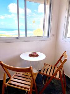 海法Sea view cozy apartment的窗户间里的一张桌子和两把椅子