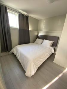 鲁安Le Cardinal的卧室内的一张白色床,设有窗户