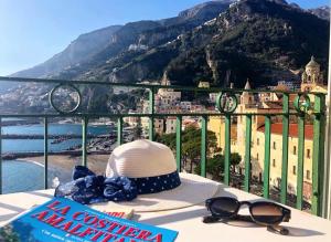 阿马尔菲Casa La Voce del Mare的坐在桌子上的一顶帽子和太阳镜,享有山景