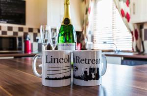 林肯Lincoln Holiday Retreat Lodge with Private Hot Tub的桌子上两个咖啡杯和一瓶葡萄酒