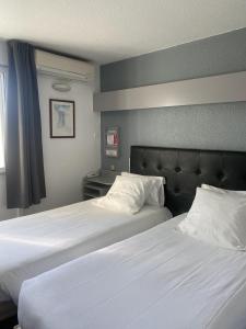 蒙德马桑Fasthotel Mont de Marsan的配有白色床单的酒店客房内的两张床