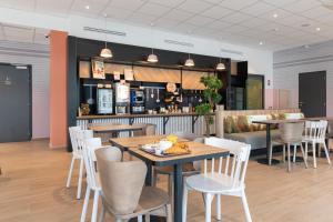 维里埃特B&B HOTELS Bourg-en-Bresse Viriat的一间带桌椅的餐厅和一间酒吧